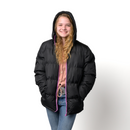 Teen wearing a wholesale bulk black puffer jacket with pink zipper on a white background
