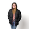 Teen wearing a wholesale bulk black puffer jacket with pink zipper on a white background